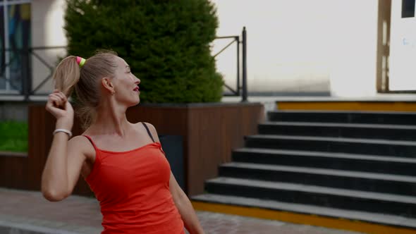 Carefree Woman is Walking in Downtown in Summer Day Playing with Her Ponytail alt