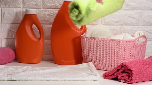 female hand rolls clean washed terry towels on white table
