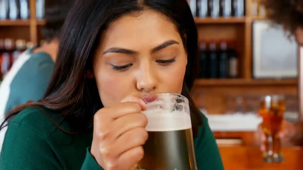 Woman having mug of beer while interacting with friends 4k alt