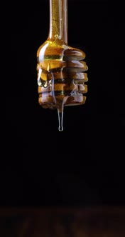 Honey dripping from spoon in front of black background alt