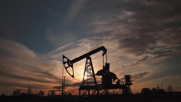 Oil pump and rig at sunset