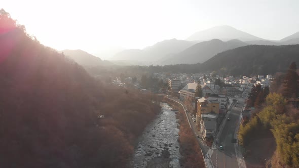 Drone flight, over small Japanese town of Nikko, misty background during golden hour with rays shini alt