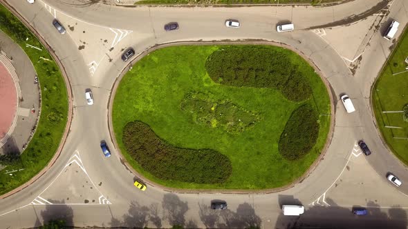 Top down aerial view of roundabout street intersection with moving cars traffic. alt