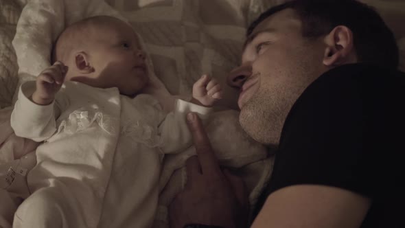 Dad with Beloved Baby Daughter Lying on Bed alt