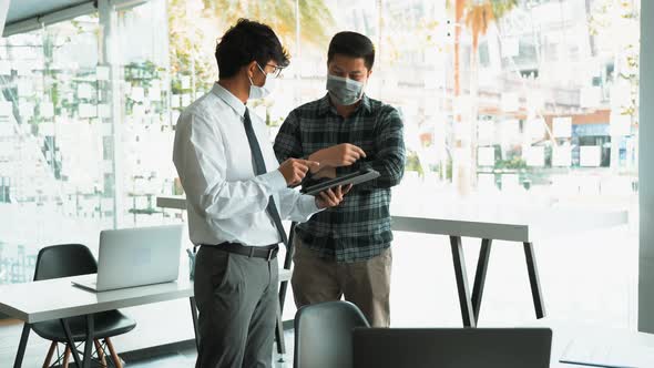 Asian colleague stood at the office and analyzed corporate data while wearing a face mask