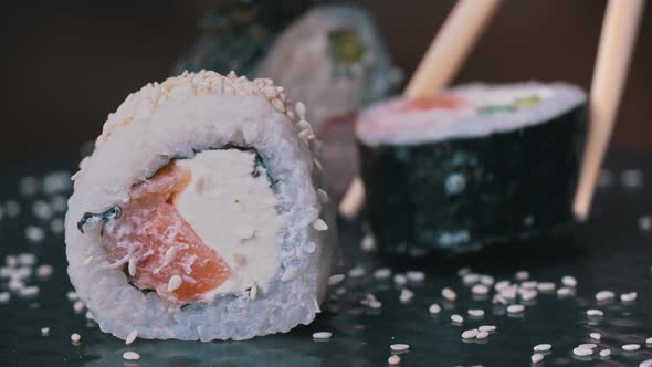 Fresh Sushi Roll with Sesame is Placed with Special Japanese Chopsticks alt