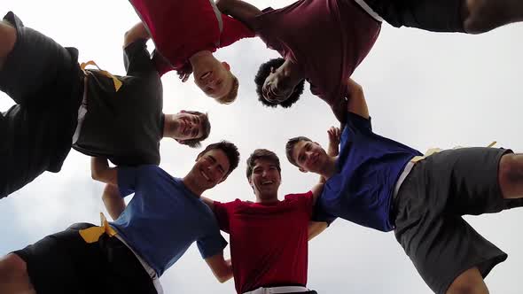 A group of young men playing flag football on the beach. alt