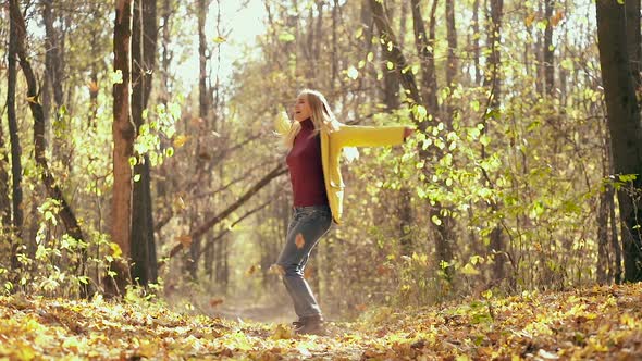 Blonde woman whirling around herself in the autumn forest.