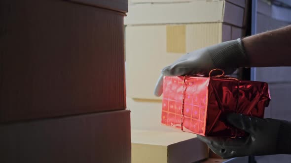 A man gloved hand takes a gift box at the store warehouse on Christmas and New Year Eve