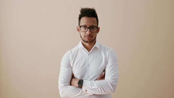 Young Man with Folded Arms Looking Confident to Camera Than Smiling