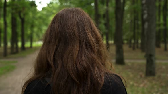 Gimbal Shot of Woman Back Walking Through Forest in Summer Time