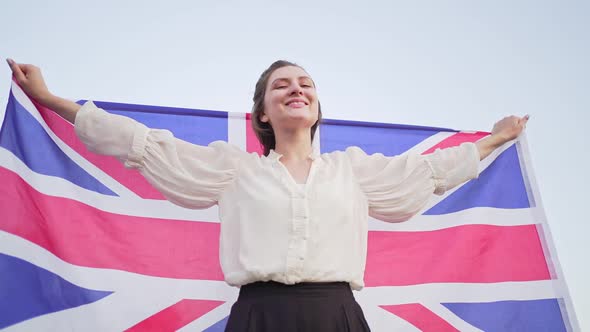 Patriot with the National Flag of Great Britain. Independent Woman Smiles and Rejoices
