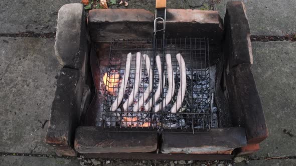 Grilling Bratwurst Sausages Preparation at Barbecue Grill Made From Burnt Bricks