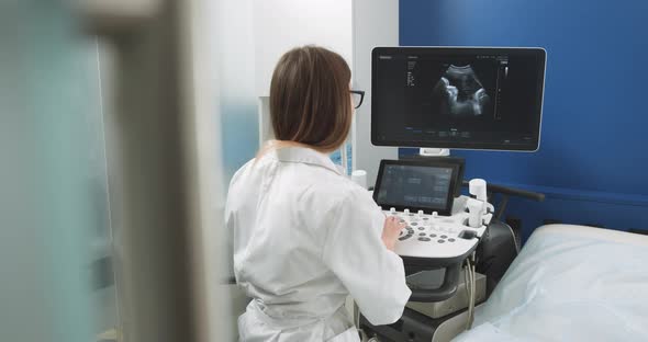 Operator of Ultrasound Scanning Machine Sitting and Looking at the Screen alt