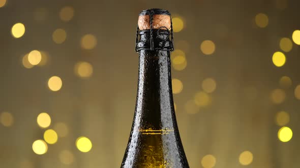 Champagne bottle closeup, rotate. Champagne bottle over Holiday Bokeh Blinking Background. alt