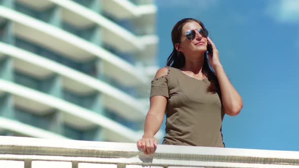 Charming Smiling Woman Enjoying Vacation on Terrace Modern Hotel and Talking Using Smartphone
