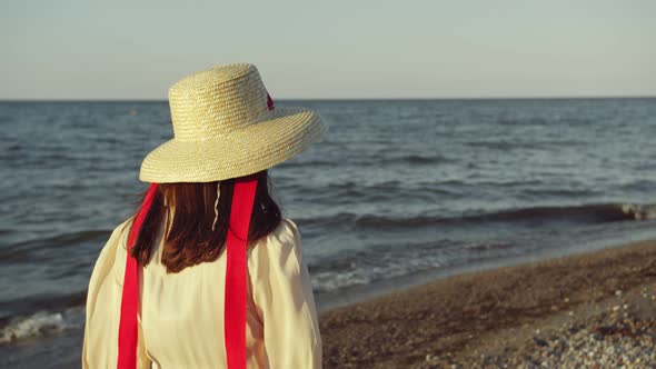 Girl in a Hat Walks Along a Beautiful Beach