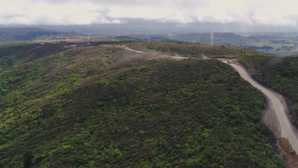 Construction of access rd for wind farm in Manawatu, New Zealand. Fly across rugged mountain top fol alt