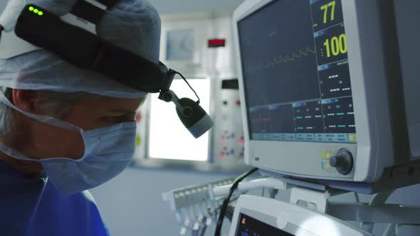 Side view of Caucasian female doctor operating medical monitor in operation theater at hospital alt