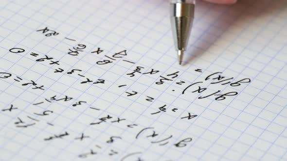 The Hand Holds a Pen and Writes a Mathematical Formula in a Notebook. Solution of Equation. The alt