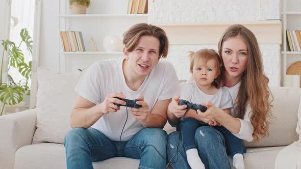 Overjoyed Caucasian Parents Father and Mother with Cute Child Daughter Infant Toddler Gamers Winners alt