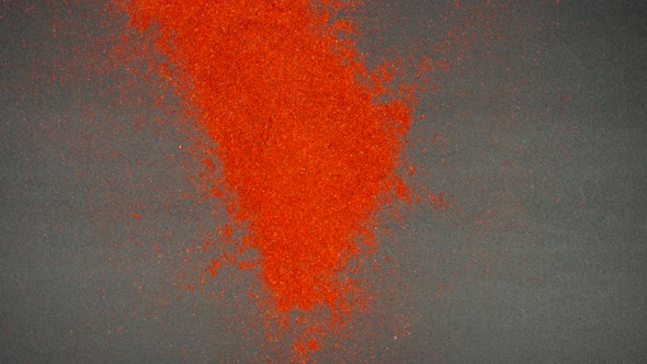 Flow of red pepper falls on a black table