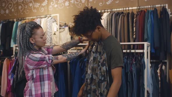 Young Multiethnic Couple Choosing Clothes in Shopping Mall alt