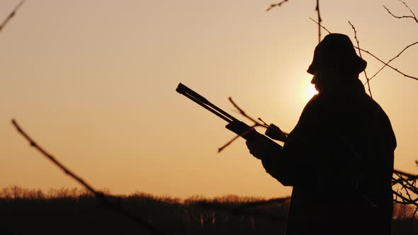 Silhouette of a Male Hunter, Hunting in the Forest, Takes Aim alt