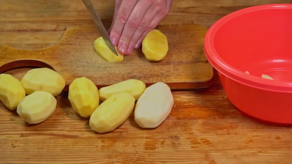 Man cuts the potato on the cutting Board sharp knife cut into slices slow motion. Closeup of hand alt