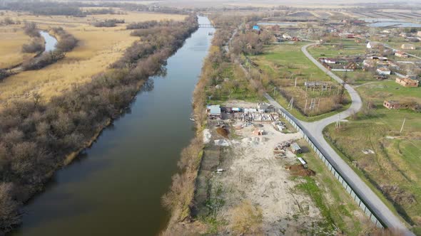 A drone flies over an abandoned warehouse along a river alt