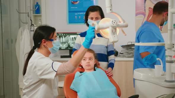 Dentistry Doctor Speaking to Kid Sitting on Stomatological Chair alt