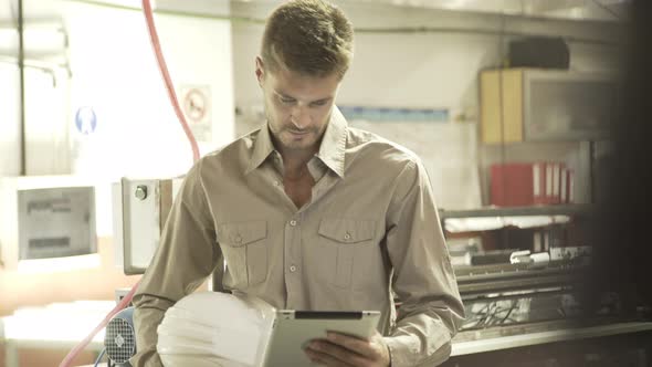 Man looking at digital tablet while working in factory alt