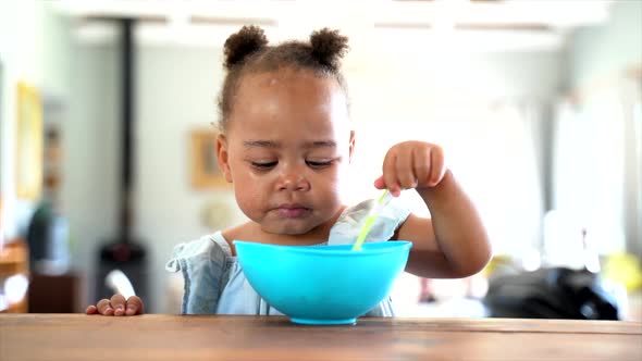 Young South African girl eating her lunch with a blue bowl alt
