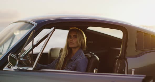 Beautiful woman in a vintage car at sunset alt