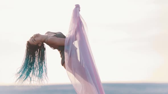 Pole Dance Outdoors - Woman with Blue Braids Spinning on the Pole with Pink Veil alt