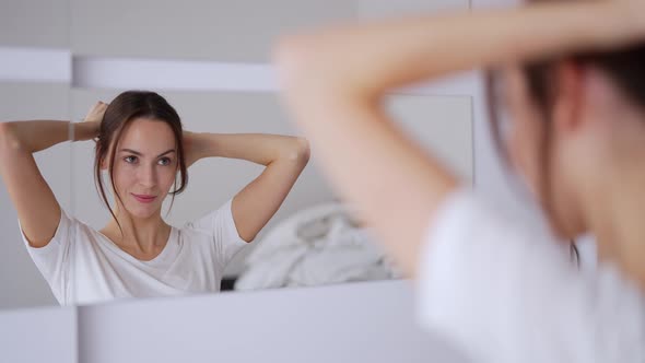 Glad Woman Doing Hair Near Mirror alt
