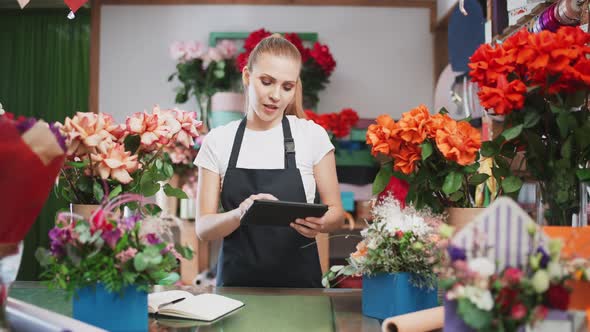 Botany and Working with Plants Florist Woman Takes Inventory in a Flower Shop a Female Uses a Screen alt