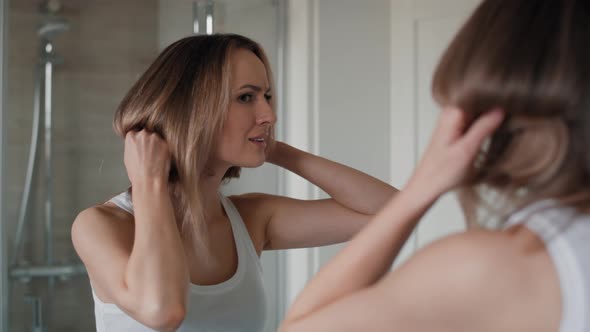 Caucasian woman checking hair condition in the bathroom. Shot with RED helium camera in 8K. alt