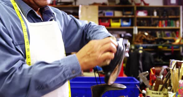 Smiling cobbler polishing a shoe alt