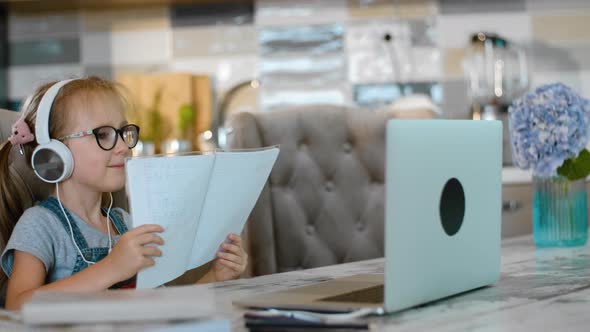 Little Girl Shows Homework Notebook to Online Tutor in Video Call Rbbro alt