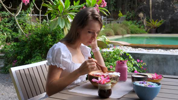 Happy Smiling Woman Eating Vegan Breakfast Acai Bowl at Outdoor Cafe alt