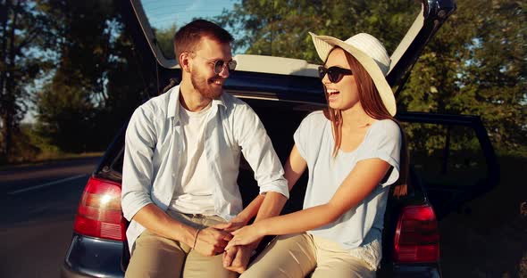 Couple Sitting in Car Trunk on Sunset