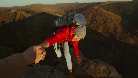 POV of Male's Hand Stretching Out and Helping Woman Hiker Reach Cliff Top By Pulling Her Up From alt
