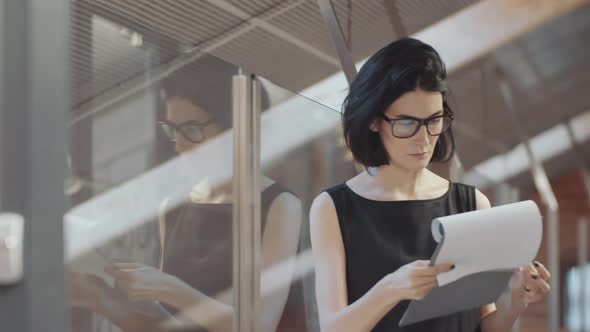 Brunette Woman Reading Business Report in Office alt