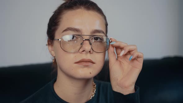 Closeup of the Freckled Redhaired Young Woman with Glasses Holding Her Hand Near Her Eyes alt