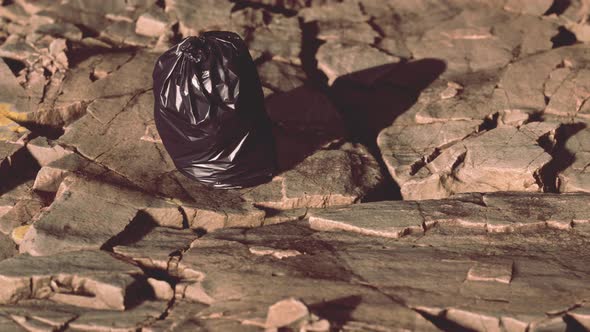 Black Trash Bag Lay on a Rocky Beach alt