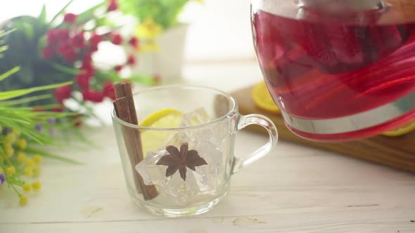 Tea is Poured Into a Glass Transparent Cup on a Wooden Table alt