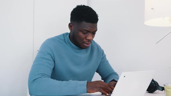 African American Black Man Sitting at the Table in Front of a Laptop Working alt