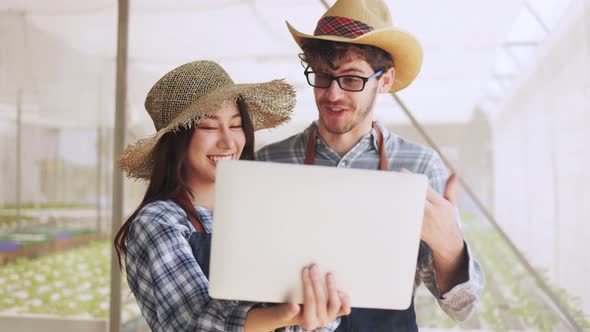 Couple farmer in apron holding and checking the quality of an organic vegetable alt