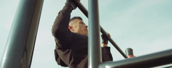Strong Man Doing Pull-Ups on Horizontal Bar Outdoors alt